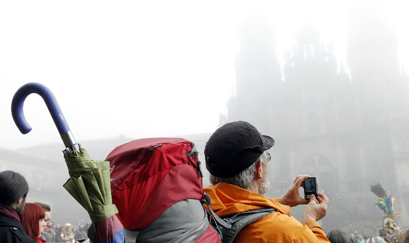 Un peregrino fotografía la catedral de Santiago oculta tras la niebla / Fotografía de Sandra Alonso