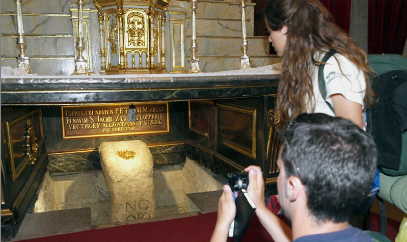 Unos turistas fotografían el Pedrón donde la tradición sitúa que se amarró la barca con los restos del Apóstol / Fotografía de Merce Ares